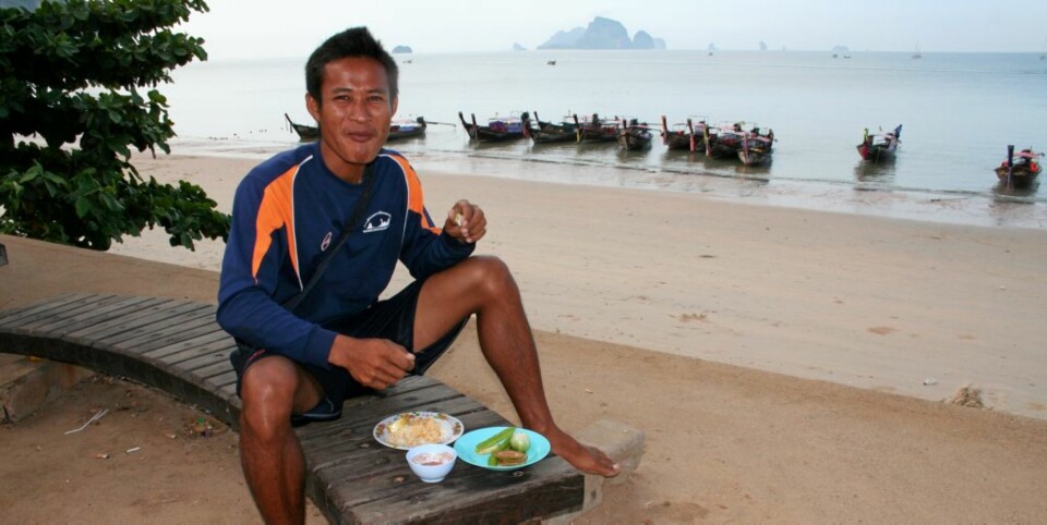 LUNSJ: Longtailbåtsjåfør Jud slapper av med en matbit ved stranda i Ao Nang.