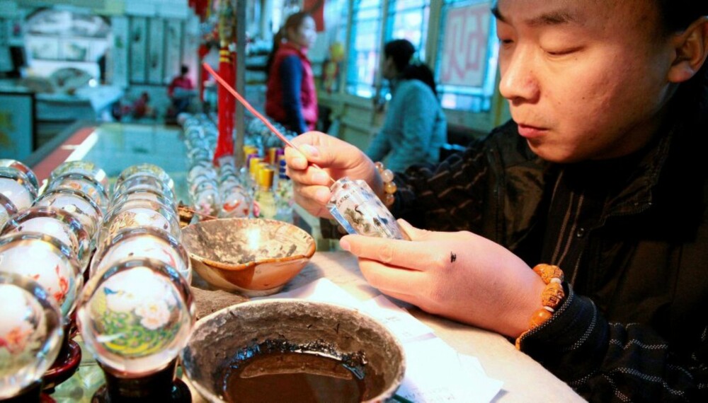MINIATYRMALER: Xu Bu har tatt opp kunsten å male på innsiden av små glassflasker fra faren og farfaren sin. Nå driver han en butikk i den sjarmerende Beijing-handlegaten Liulichang.