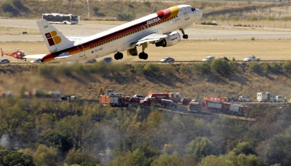 153 DØDE: Et passasjerfly tar av fra flyplassen i Madrid. I bakgrunnen ser man ulykkesstedet der 153 døde i en flyulykke onsdag ettermiddag.