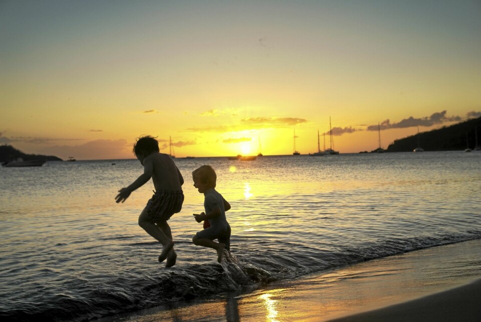 SOLNEDGANG: Det er noe magisk med solnedgangene her, selv om disse guttene på den offentlige stranden i Bouillante ikke får det med seg.