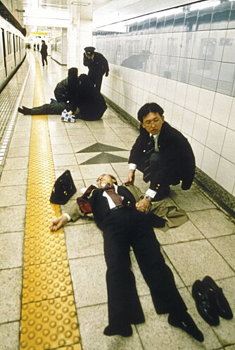 En overlevende etter nervegassangrepet på Tokyos T-bane passer på liket av en medreisende som ikke var like heldig.