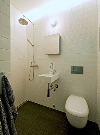 ÅPNER ROMMET: I det lille badet samles alt utstyr på én vegg. Rennesluket fra Unidrain gir ensidig fall og skrå gulvflater, og da kan man også bruke bare slike store, 30 x 60 cm Vitra gulvfliser. En 28 cm bred og 40 cm dyp Boxo vask bygger ut i rommet. ÅPNER ROMMET: I det lille badet samles alt utstyr på én vegg. Rennesluket fra Unidrain gir ensidig fall og skrå gulvflater, og da kan man også bruke bare slike store, 30 x 60 cm Vitra gulvfliser. En 28 cm bred og 40 cm dyp Boxo vask bygger ut i rommet.