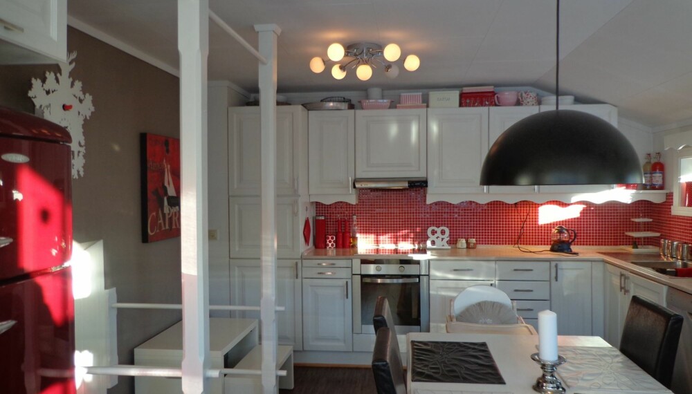 I det hyggelige kjøkkenet er det plass til både store og små. Det røde fra mosaikkflisene er tatt opp i kjøleskapet.