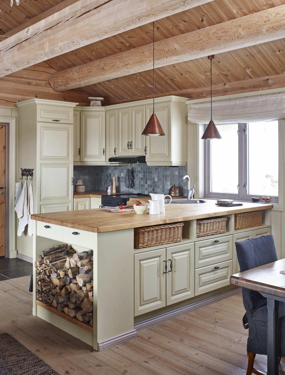 FLOTT KJØKKEN: Kjøkkenet har Kari tegnet selv, men det er Atico som har laget det. Legg merke til kobberlampene over kjøkkenbenken. Kobber går igjen i takrenner, utelamper og altså på kjøkkenet. En vedhylle som en integrert del av kjøkkeninnredningen er både praktisk og dekorativt. FOTO: Sveinung Bråthen