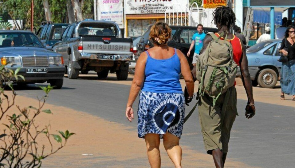HÅND I HÅND: En middelaldrende hvit kvinne går hånd i hånd med en ung gambier i byen Kololi. På gaten her er sexturismen åpenlys.