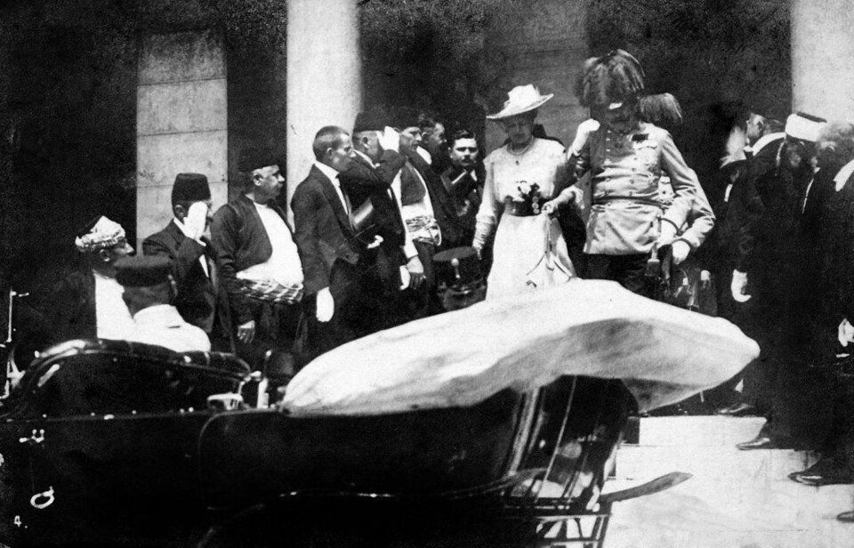 Franz Ferdinand og hans kone i ferd med å gå ombord i bilen ved rådhuset i Sarajevo. Minutter senere var begge skutt av Garvilo Princip, en bosnisk serber som var medlem av en organisasjon kalt Unge Bosnia. Organisasjonen var en terrororganisasjon som jobbet for et samlet Jugoslavia, fritt fra Østerrike-Ungarn, og hadde indirekte tilknytninger til den serbiske regjeringen.