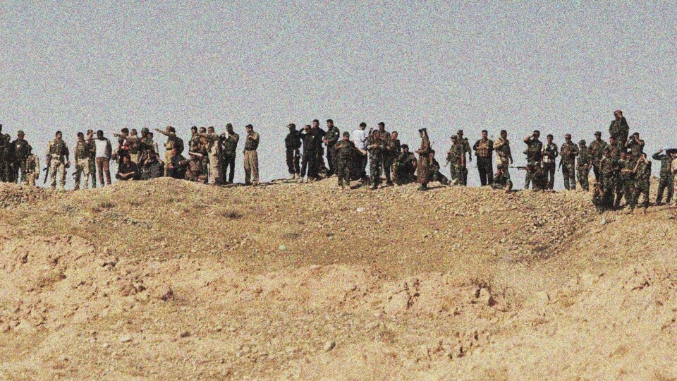 OVERSIKT: Medlemmer av den kurdiske kampstyrken Peshmerga står på linje på en bakketopp mens de ser kampene utfolde seg i byen Jalowla et par tusen meter unna.
