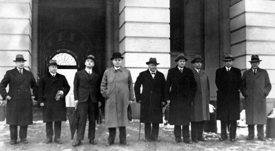 Fra Venstre: Finansminister Adolf Indrebø, forsvarsminister Fredrik Monsen, utenriksminister Halvdan Koht, statsminister Johan Nygaardsvold, landbruksminister Hans Ystgaard, handelsminister Alfred Martin Madsen, sosialminister Kornelius Bergsvik, undervisningsminister Nils Hjelmtveit og justisminister Trygve Lie.