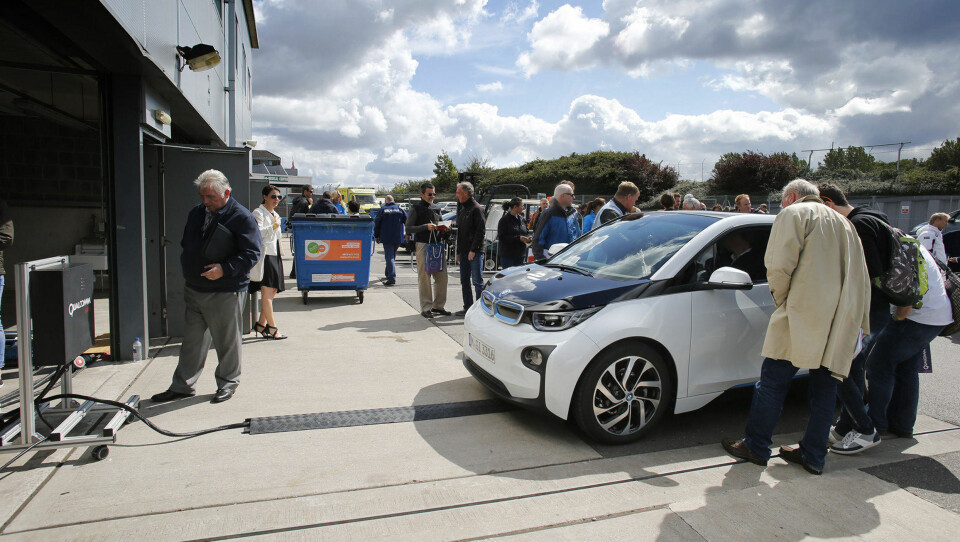 En BMW i3 står på en trådløs ladestasjon.