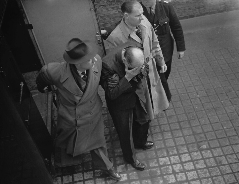 ENDELIG TATT: John Christie gjemmer ansiktet sitt for pressen på vei til retten.