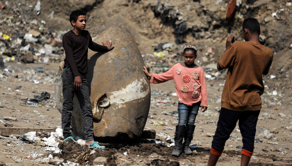 FOTOSHOOT: Lokale barn poserer foran deler av statuen som antakelig viser farao Ramses II.