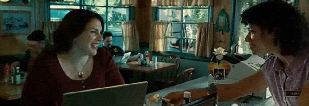Stephenie Meyer sitter i front, mens Bella snart kommer inn døra for å spise lunsj med faren (politimannen i bakgrunnen).