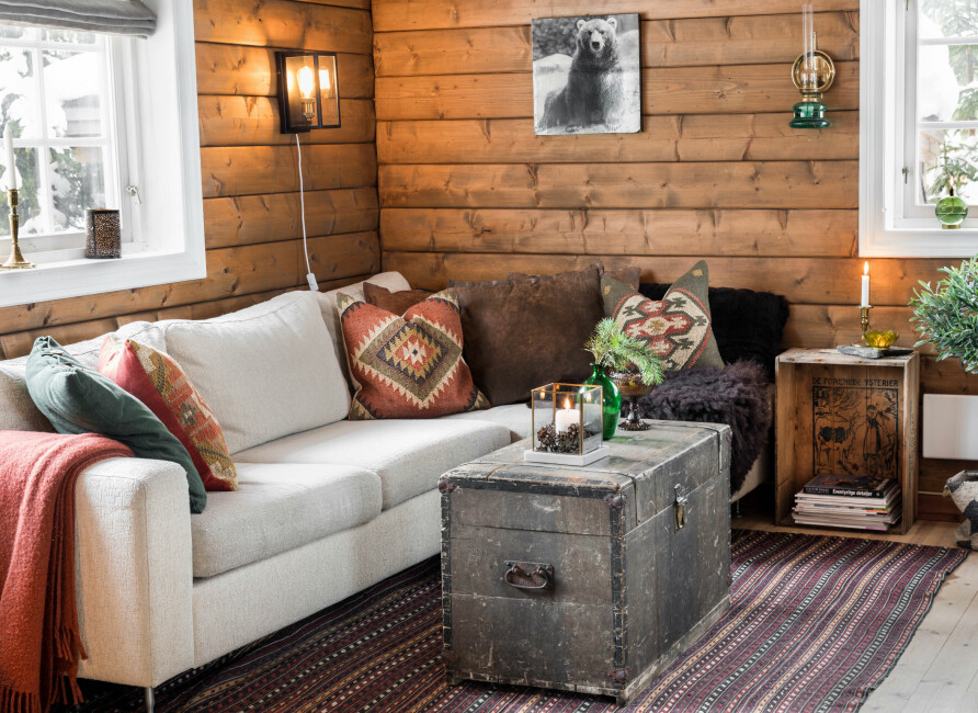 Stuekrok. Bolia-sofaen de hadde hjemme, ble flyttet til hytta. Bordet er en Amerikakoffert de fant på Finn, og kelimteppet kjøpte Richard i Iran for mange år siden.