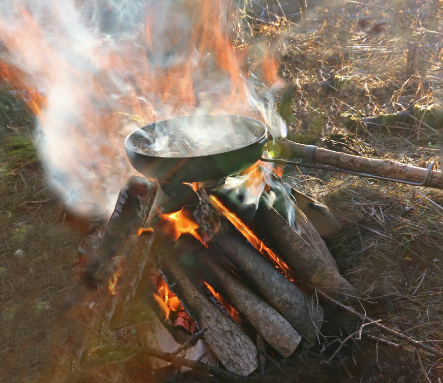 KAFFEBÅLET På et brannsikkert underlag som stein eller grus legges tre–fem stokker på rundt 10 cm diameter ved siden av hverandre. Disse behøver ikke – som resten av bålveden – være helt tørre. På tvers av disse stokkene legges to tynnere stokker med åpning mellom, og tilsvarende oppå disse igjen. I midten plasseres never, mange små, tørre pinner eller annet opptenningsmateriale som antennes. Fordelen med dette bålet er at du kan sette kaffekjelen rett nedpå bålet når det har tatt fyr. (Foto: Dag Kjelsaas)