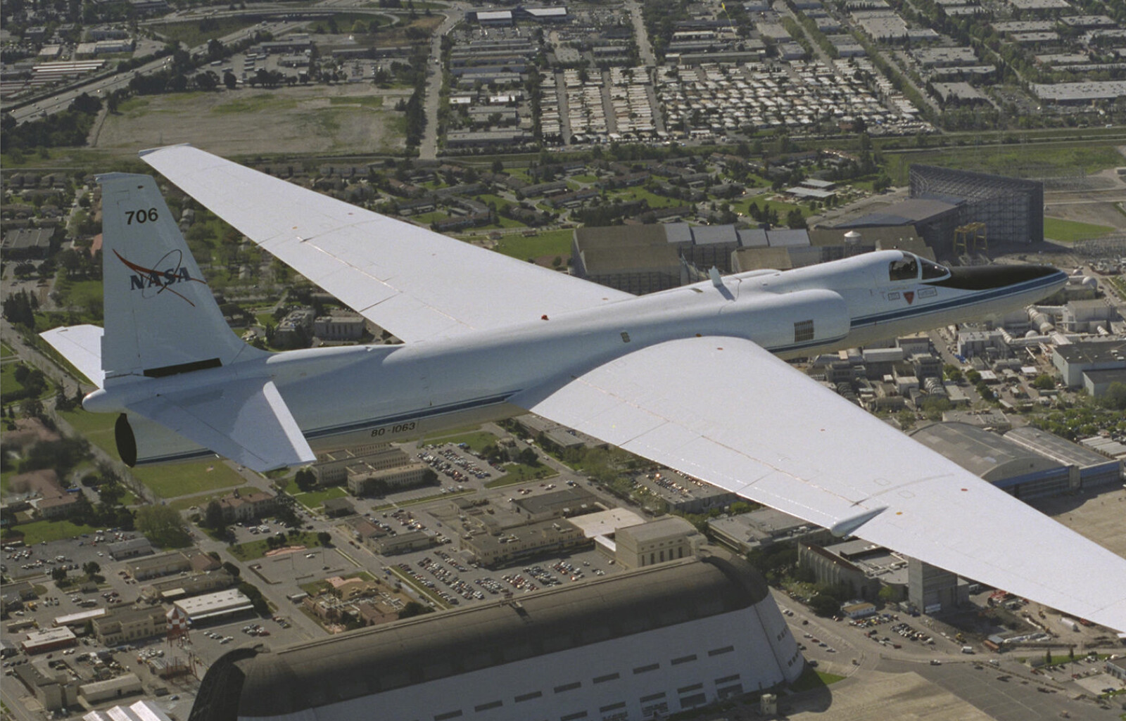 <b>HANGAR ONE:</b> Et Lockheed ER-2 (basert på spionflyet U-2) flyr over Moffett Federal Airfield i 1996. Den store bygningen er Hangar One. 