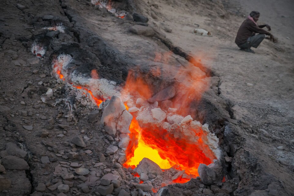 VARMER SEG OM VINTEREN: En innbygger i Jharia varmer seg på flammene som står opp av sprekken i jordskorpa like ved landsbyen Bokapahti.