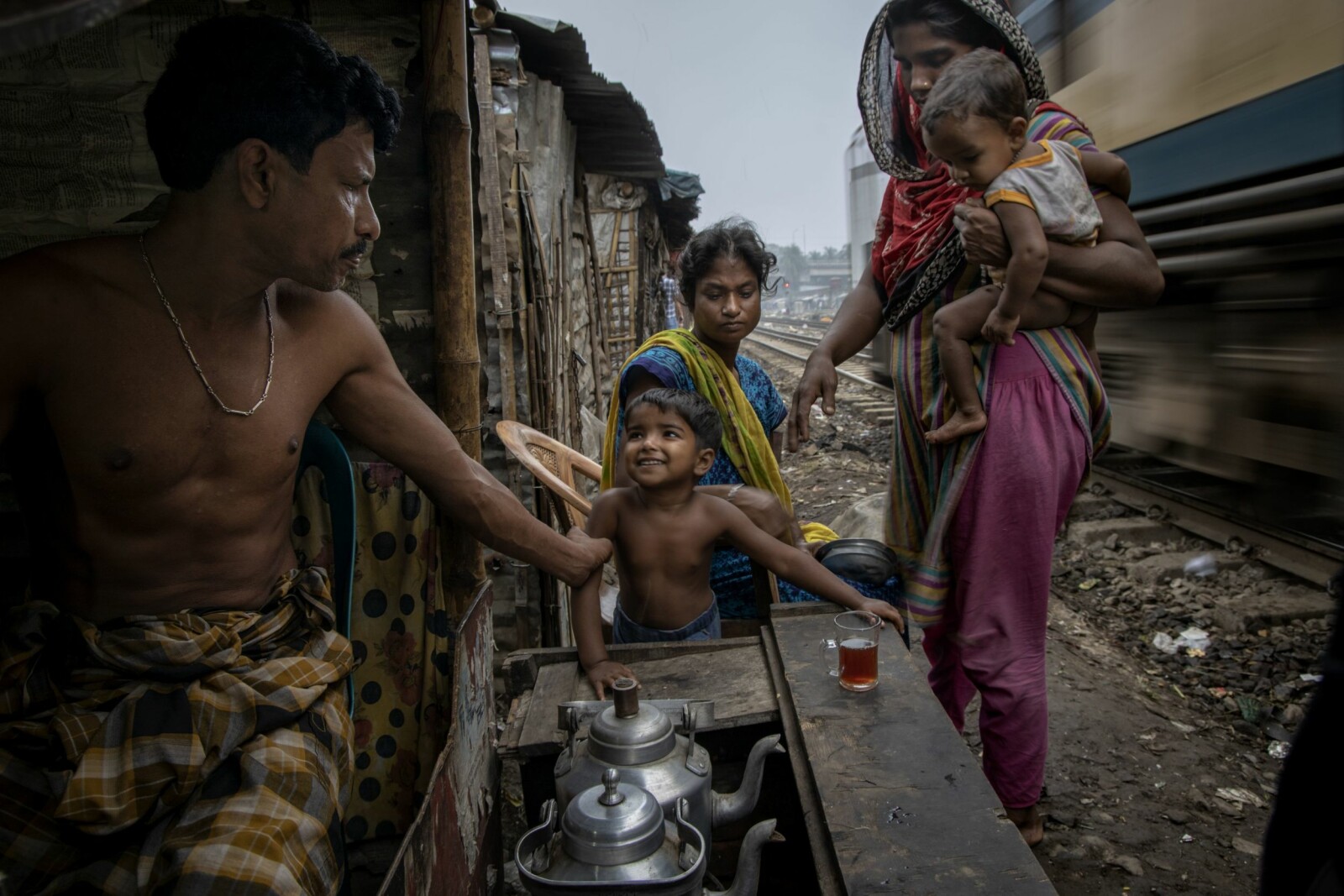 <b>HOLDER PÅ SØNNEN:</b> Kokon tar automatisk et tak i armen på sin yngste sønn i det et tog feier forbi hans lille te-sjappe i slummen av Dhaka.