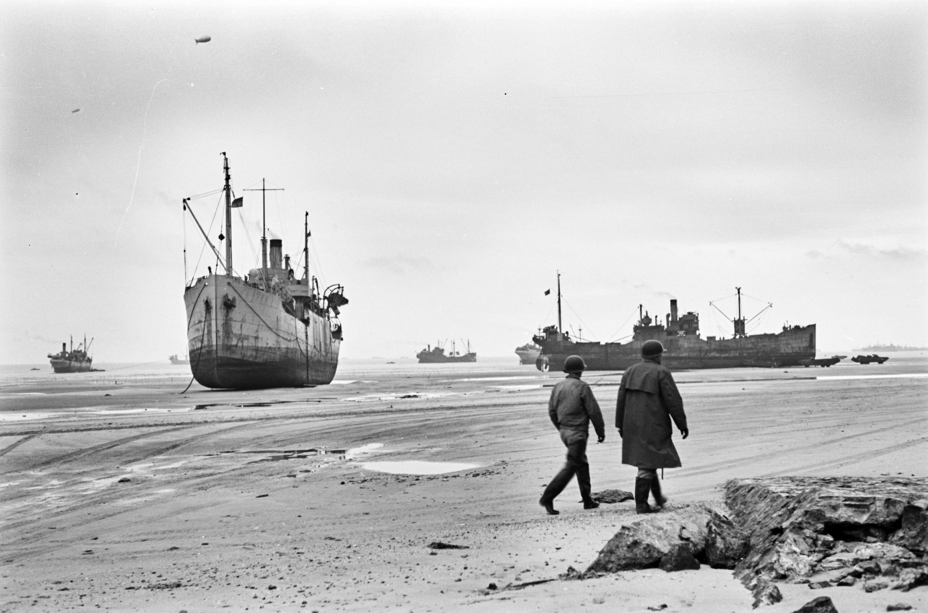 PÅ TRYGG GRUNN: De norske handelsskipene Fagerbro (t.v.) og Heien (t.h.) var blant de 50 norske sivile fartøyene som bidro til at invasjonen i Normandie lyktes. Her under lossing ved lavvann utenfor det amerikanske avsnittet av stranden.