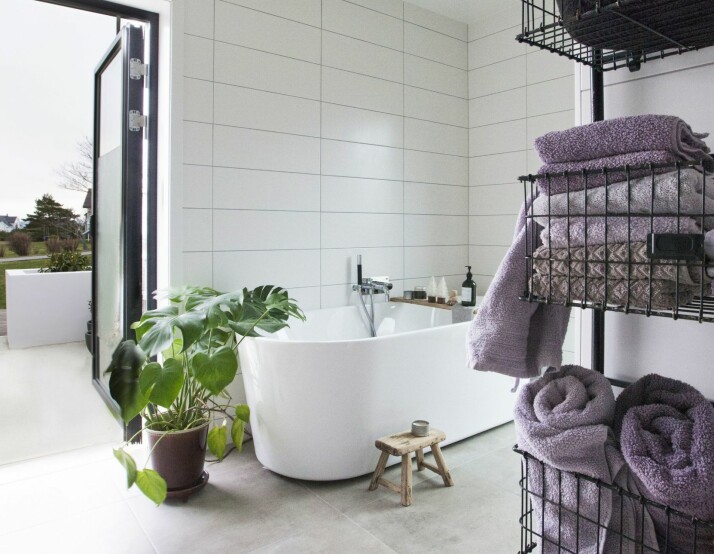 BAD MOT HAVET: Ikke alle kan stå med døren åpen ut mot havet mens man sminker seg! Badet er en kombinasjon av fliser, våtromsmaling og tapet. Flisene er fra Fagflis. Badekaret heter Ellipse og er fra Viking Bad.