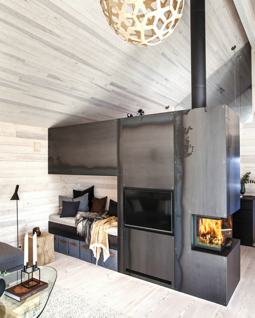 ROMDELER: I midten av allrommet står den flerfunksjonelle romdeleren med bl.a. innebygd dagseng, lagringsplass, lufting til peis, varmepumpe, vednisje og tre høyskap på kjøkkenet. Kurvene er fra Stich Haltig på Etsy.com. Veggene er kledd med kvistfri furupanel behandlet med lys voks, som reduserer gulning. Gulvet er Dinesen Douglas gran i hele lengder, med bredde på 35 cm.