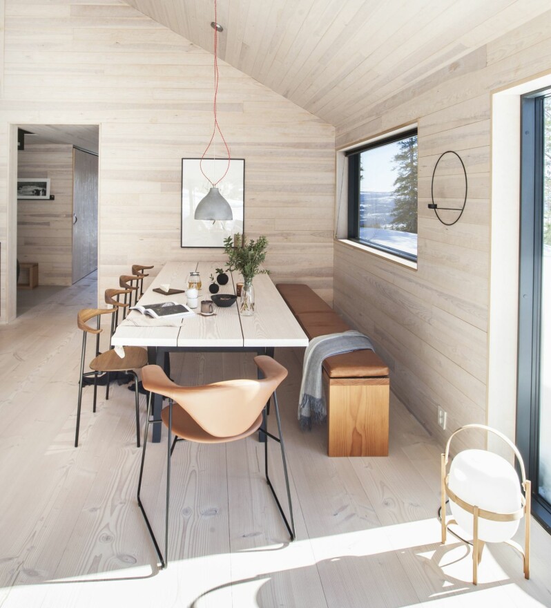 SPISEPLASS: Her står et selvlaget bord av rester av Dinesen Douglas plank, som også er brukt til gulvet, understellet er i svart ask. Benken er også laget av Dinesen-gulvet, og en skinnpute sydd på mål gjør det behagelig å sitte lenge. Skinnet er Old english tan leather levert av Love Leather UK. Spisestuestolene er CH88, design Hans Wegner, i oljet, røkt eik med svart pulverlakkert understell, produsent er Carl Hansen. Den brune stolen er Masculo dining chair fra Gubi. Lampen er Heavy Pendant, design Benjamin Hupert for Decode London. På gulvet står Miguel Milas lampe Cesta fra Santa & Cole. Kopper og tekanne fra Bolina.