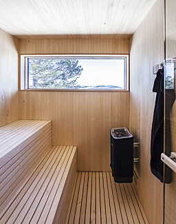 BADSTU: Innenfor badet er det bygget badstu i ospepanel og spiler. Også her kan man nyte nærhet til naturen, takket være vinduet i enden av rommet. Døren inn er en badstudør fra Tylö DGL med klart glass og karmer i kvistfri, lys osp som matcher panelet og spilene. BADSTU: Innenfor badet er det bygget badstu i ospepanel og spiler. Også her kan man nyte nærhet til naturen, takket være vinduet i enden av rommet. Døren inn er en badstudør fra Tylö DGL med klart glass og karmer i kvistfri, lys osp som matcher panelet og spilene.