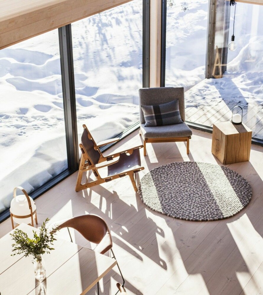 UTSIKT: Utsyn fra hemsen og ned til oppholdsdelen av hytta. Nærmere naturen kommer man nesten ikke. Den grå stolen er Hans J. Wegners GE370 som i dag produseres av Getama. Stolen i svart skinn er Hunting Chair, designet av Børge Mogensen i 1950, produsent er Fredericia. Gulvteppet heter Karianne og er fra Molekule.