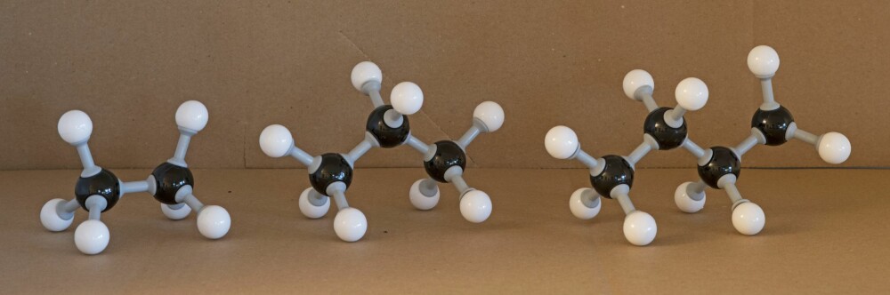 <b>MO­DEL­LER:</b> Fra venst­re: etan, pro­pan og bu­tan­mo­le­kyl, med svar­te kar­bon­ato­mer og hvi­te hyd­ro­gen­ato­mer. Vi ser at an­tall hyd­ro­gen pr. kar­bon­atom blir la­ve­re når mo­le­ky­let blir leng­re.