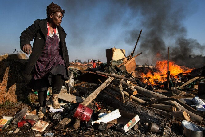 <b>JEVNET MED JORDEN:</b> Tusenvis av sørafrikanere holder til i ulovlige bosetninger utenfor storbyene. Denne kvinnen leter etter noe å redde fra ruinene etter at De røde maurene har knust de primitive husene til pinneved. 