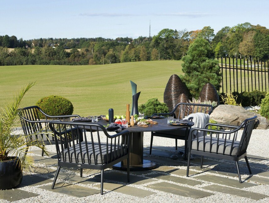 ITALIA: Det er ikke vanskelig å forstå at Lisas besøkende tenker på Toscana når de ser utover de bølgende jordene. De lette aluminiumsmøblene er kjøpt hos Wermlandsmöbler i Årjäng. Den runde store bordplaten er laget av Hjemmelagde møbler i Rakkestad, mens de tre store bambuslyktene i organiske kongleformer er fra Bali. Lisa har oljebeiset dem selv, så de tåler å stå ute.