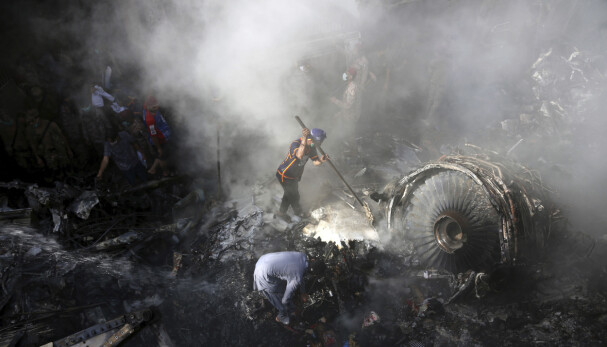 VOLDSOM KRASJ: Rester av flyet er synlig under opprydningsarbeidet i et boligområde i Karachi (AP Photo/Fareed Khan, File)