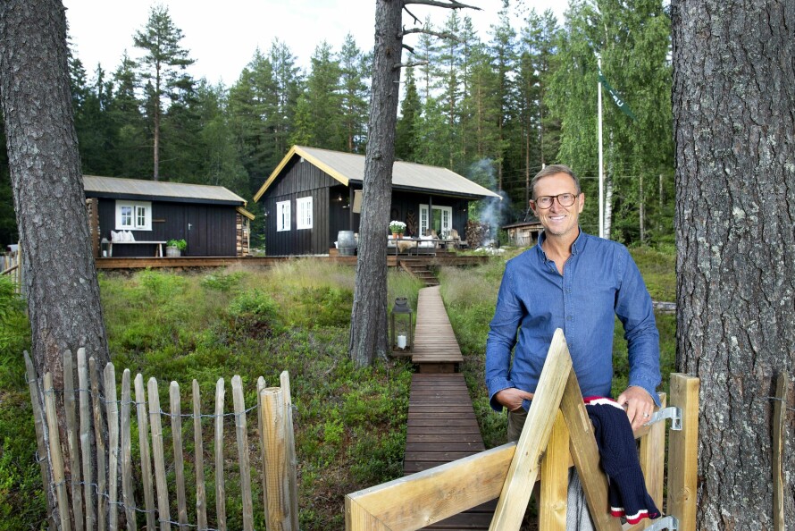 VELKOMMEN: Halvor Bakke har forvandlet den slitne hytta til en oase. Det nylig oppførte annekset til venstre har innvendig bod og bad. Boblebu har også fått flaggstang med spesialdesignet flagg. – Jeg er mest fornøyd med uteområdet, terrasseløsningen og promenadestien, sier Halvor.