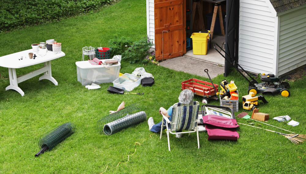 En kvinne er avbildet mens hun tar en pause fra å rydde hageredskaper og gjenstander.