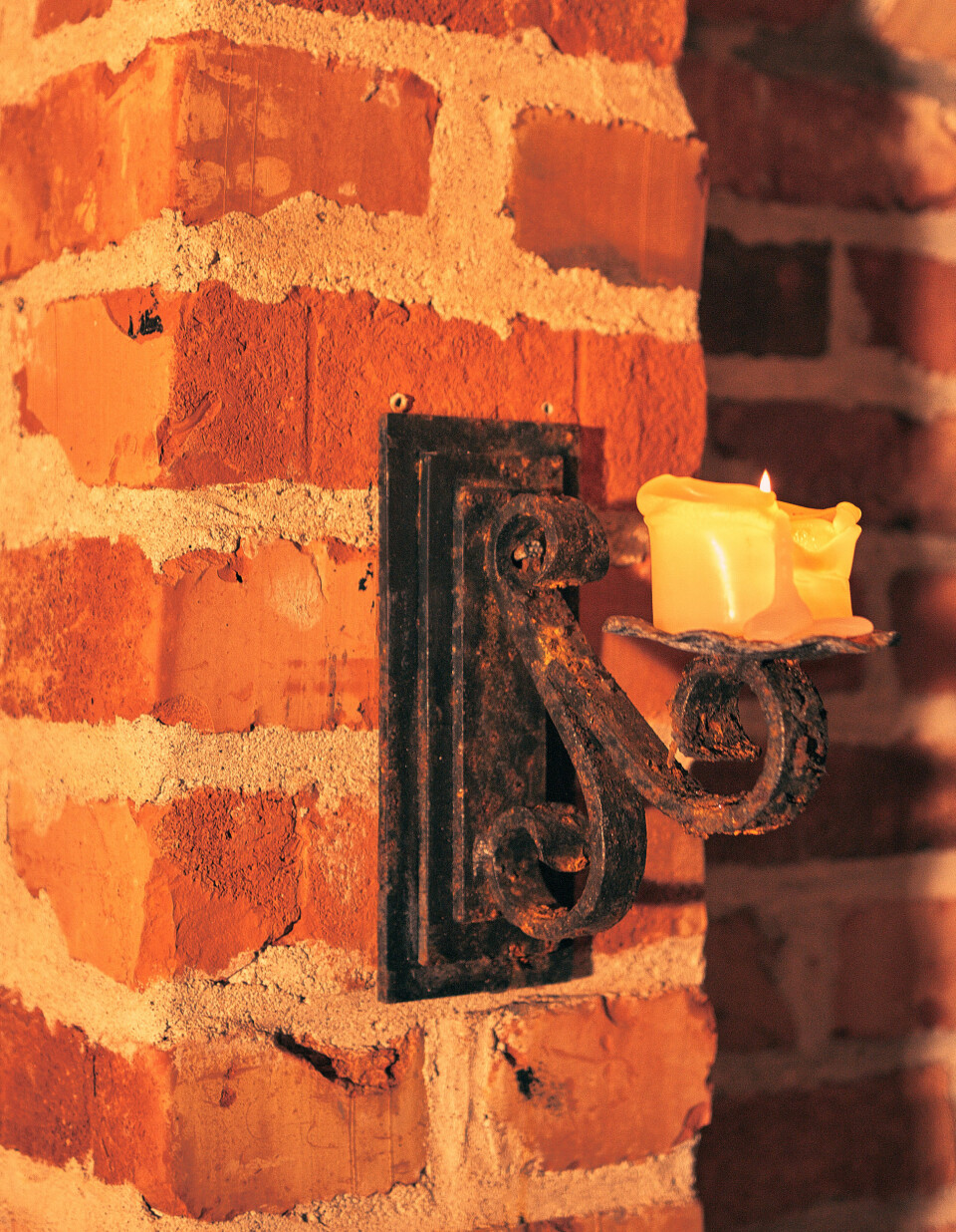 PYNT: Belysningen besørges for det meste av talglys på holdere kjøpt inn fra bruktbutikker. Det samme gjelder jernkandelabrene i taket.