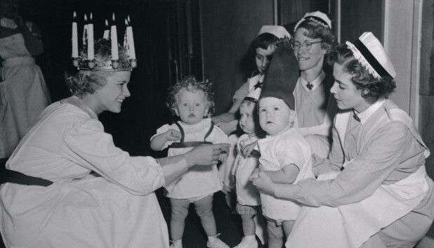 Et arkivbilde viser levende lys på hodet til Stockholms utvalgte Lucia i 1955, Monica Björkman som besøker pasienter på et barnesykehus på luciadagen. Luciafeiringen har tradisjonelt stått svært sterkt i Sverige.