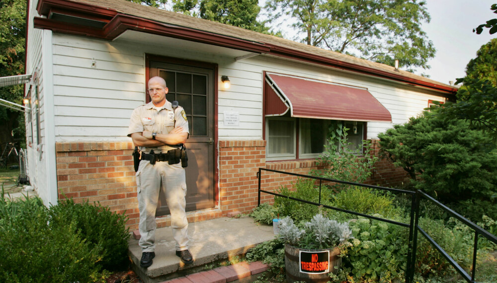 VAKTHOLD: En politimann holder vakt utenfor boligen til Dennis Rader etter arrestasjonen, mandag 11. juli. 2005. Foto: AP Photo/Orlin Wagner / NTB