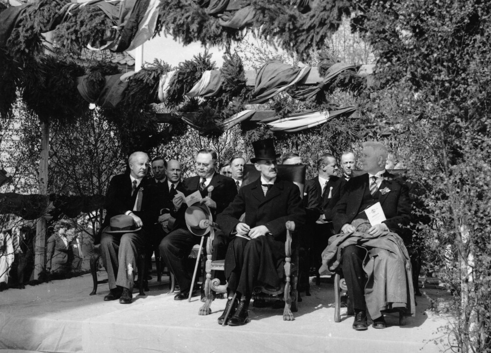 <b>MED HATT:</b> Grunnlovens 125-årsjubileum feires på Eidsvoll i 1939. Kong Haakon og statsminister Johan Nygaardsvold lytter til talene. Kongen kan etter hatteregulativet beholde hatten på, mens Nygaardsvold er i ferd med å miste sin.