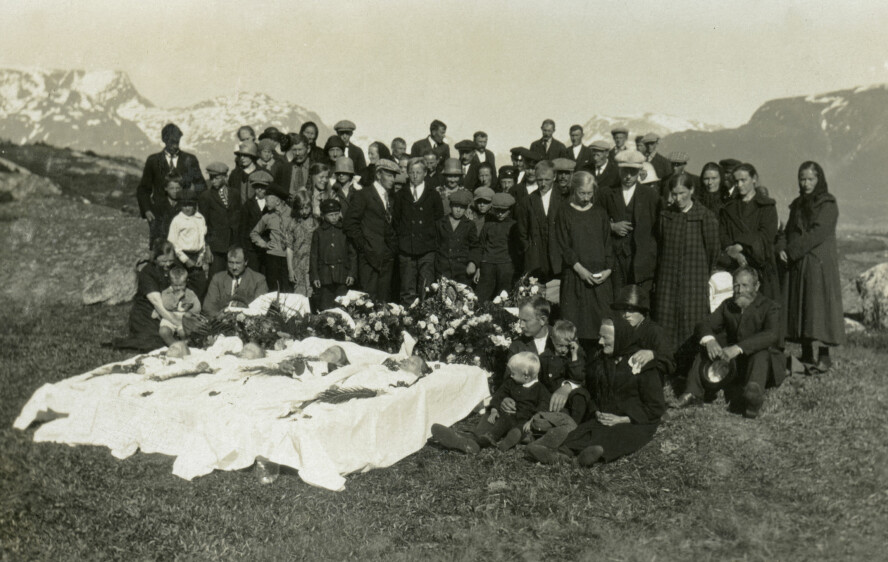 TRAGEDIEN: I de fire åpne kistene ligger Elise Pedersen (42), døtrene Sigrid (11) og Charlotte (19) og sønnen Aksel Hedley (9). Ved siden av kistene sitter enkemannen Peder Martin Kiil Pedersen (44) omgitt av fem gjenlevende barn og sørgende bygdefolk.