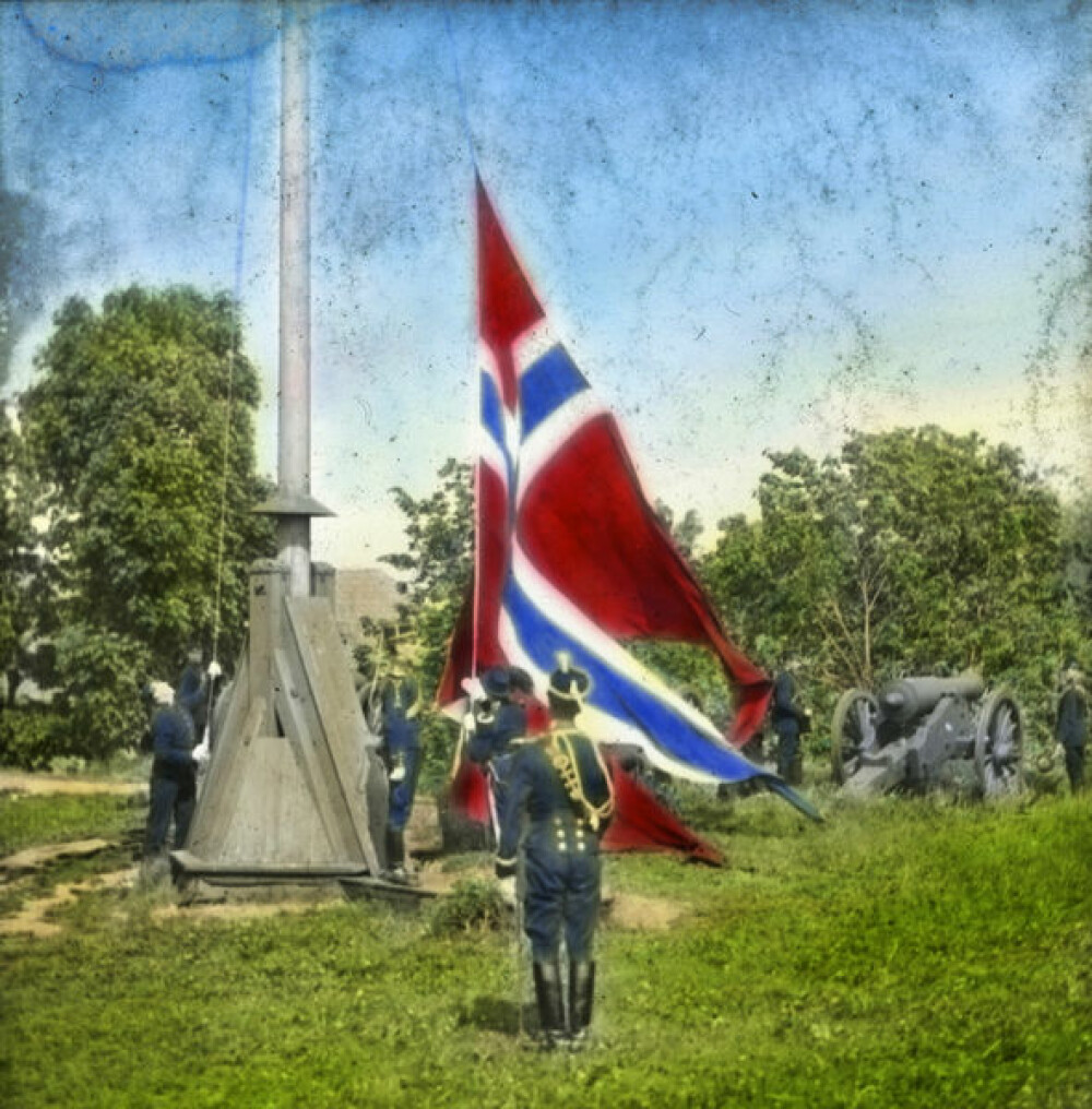 TIL TOPPS: Det norske flagget heises på Akershus festning i forbindelse med unionsoppløsningen i 1905. Fotografiet er tatt av Anders Beer Wilse og senere håndkolorert.