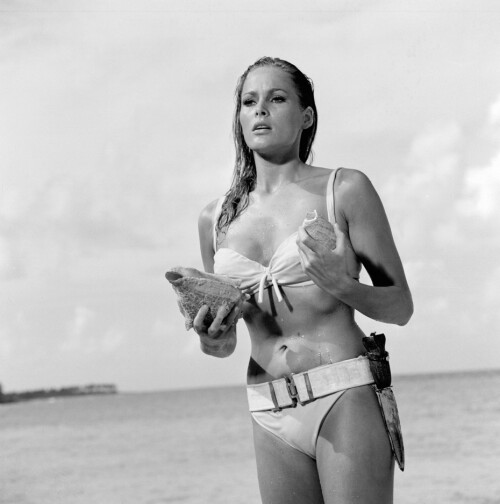 <b>URSULA ANDRESS, 1962:</b> Sveitsiske Ursula Andress steg opp av vannet som Honey Ryder i den aller første James Bond-filmen, «Dr. No». Hun hadde både konkylie, kniv og en aksent som var såpass ille at stemmen måtte dubbes – men først og fremst hadde hun en hvit bikini. Scenen er blitt ikonisk, og bikinien er i flere kåringer utropt til verdens mest berømte. Andress solgte den på auksjon for 35 000 pund i 2001. <br/>I originalromanen til Ian Fleming hadde Honey Ryder bare på seg beltet, for øvrig.