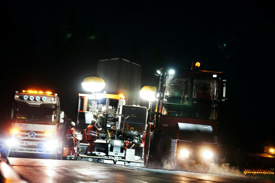 TRANGT OM PLASSEN: Oppunder ti lastebiler går i skytteltrafikk mellom asfaltverket i Moss og den flombelyste asfaltutleggeren på fylkesvei 124 ved Askim. I løpet av natten legges drøyt 1000 tonn asfalt på veien.