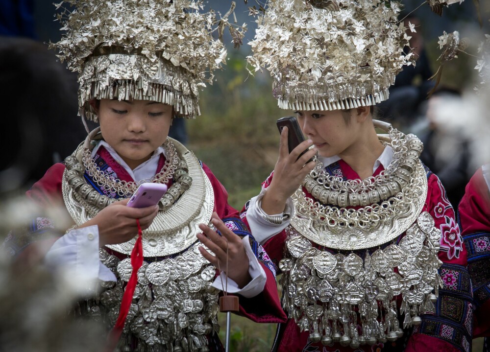 <b>FESTKLEDD PÅ NETT:</b> Kledd etter gammel tradisjon, men jentene sjekker utseende via kamera på moderne mobiltelefoner. Møte mellom det nye og gamle Kina er påfallende på landsbygda i Guizhou. 