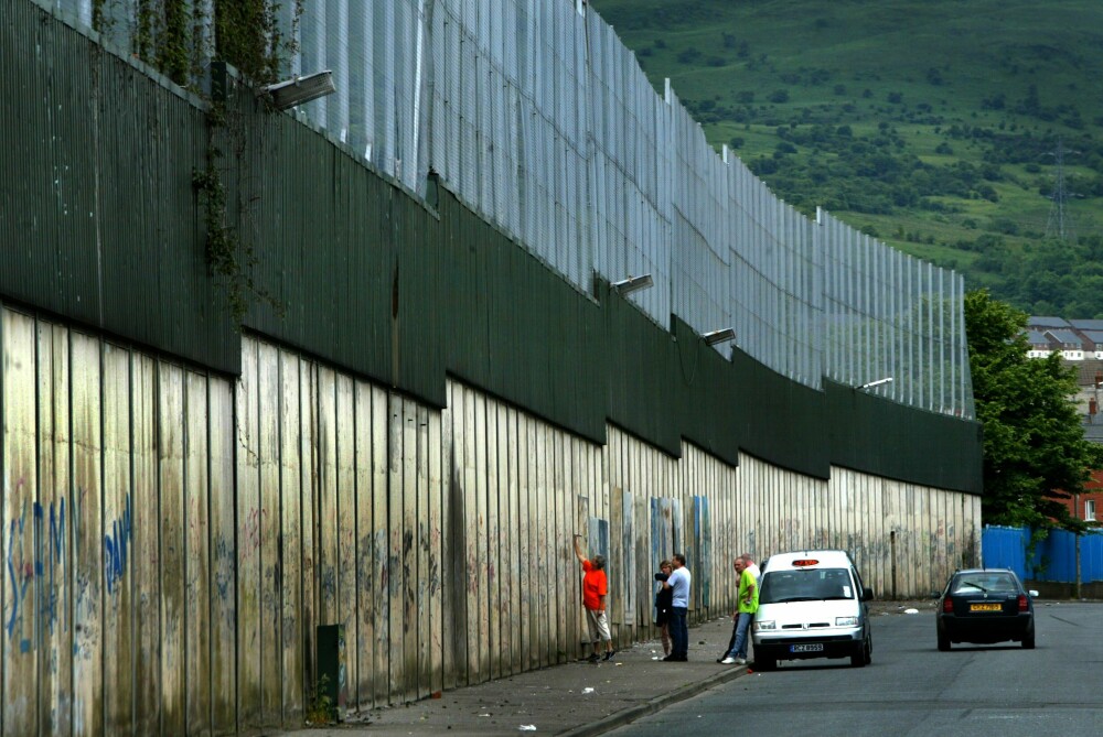 Peace Wall: Siden konflikten i Nord-Irland eskalerte på tampen av 60-tallet, har protestantiske Shankill Road og katolske Falls Road vært selve symbolene på konflikten i Nord-Irland, gjerne omtalt som The Troubles. Gatene var i mange år skilt av en diger mur, kalt The Peace Wall. Slik murer finnes flere steder i Nord-Irland, særlig i Belfast og Derry, der den betente konflikten har hatt sine mest voldsomme utspill. Alle murene skal etter planen være fjernet innen 2023 i henhold til den offentlig vedtatte strategien "Together: Building a United Community Strategy".