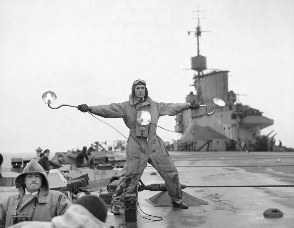 <b>VIKTIG MANN:</b> Skipets «Landing signal officer» viser vei for en pilot som skal lande på britiske HMS Illustrious under andre verdenskrig. I 1950-årene ble mennene erstattet av optiske landingssystemer der rader av lys tennes.