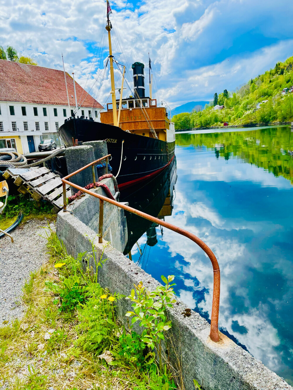 <b>IDYLLISK:</b> Gammel fjordabåt ved kai i Bjørsvik. I bakgrunnen skimtes en av Skandinavias største trebygninger, som før ble brukt som mølle og hermetikkfabrikk.