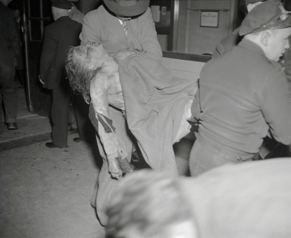 FORBRENT: En ung kvinne blir båret ut av brannruinen.