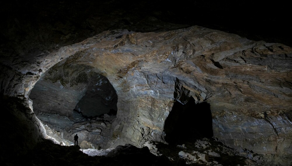 MEKTIG: En liten fotograf står på en stein midt i den enorme Svarthammarholas mørke verden. Å få oppleve denne grotta kan nå tilhøre fortiden, i og med at rasfaren har økt betraktelig. Litt merkelig er det å forestille seg at denne kolossale grotten først ble utforsket sent på 1960-tallet og ikke kartlagt før i 1970.
