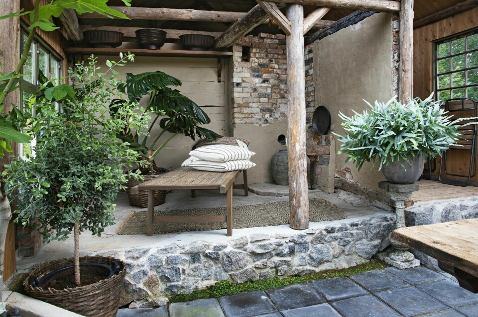 Der essen tidligere var, er det i dag et opphøyd gulv rammet pent inn med en mur av naturstein. Et avslappende område med plass til en daybed fra Hedegaards. De grågrønne treet er maorimyrt fra New Zealand.