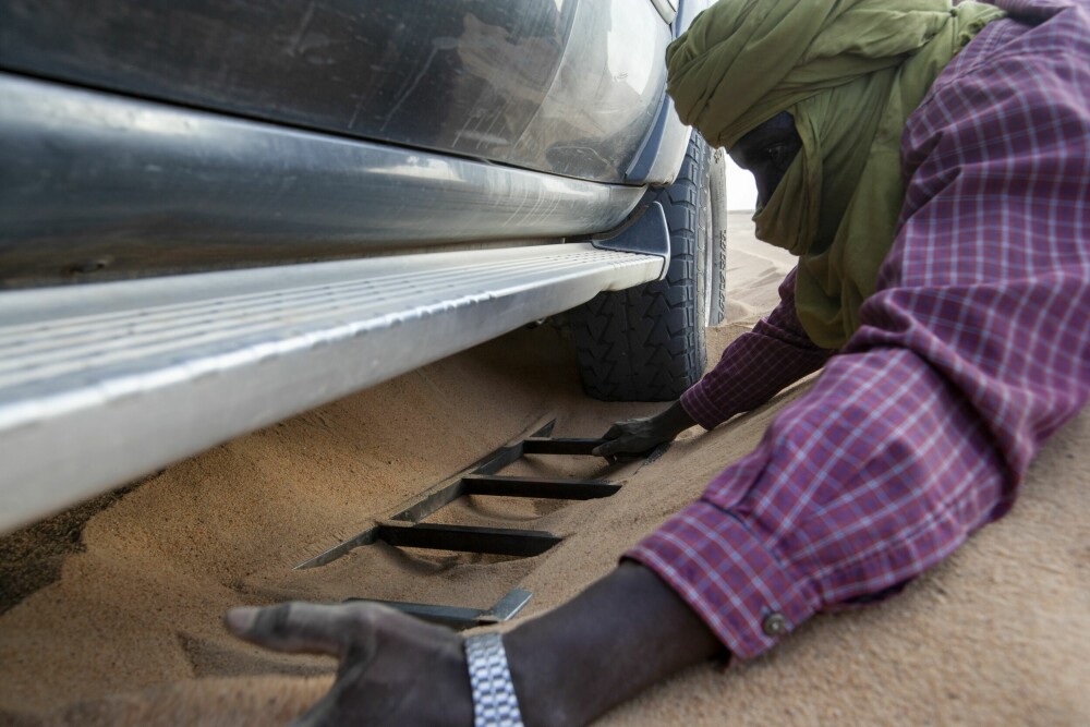 <b>UT MED SANDSTIGENE:</b> Sjåføren legger ubekymret ut sandstiger under hjulene på bilen, da vi sitter bom fast langt ute i Sahara ørkenen.