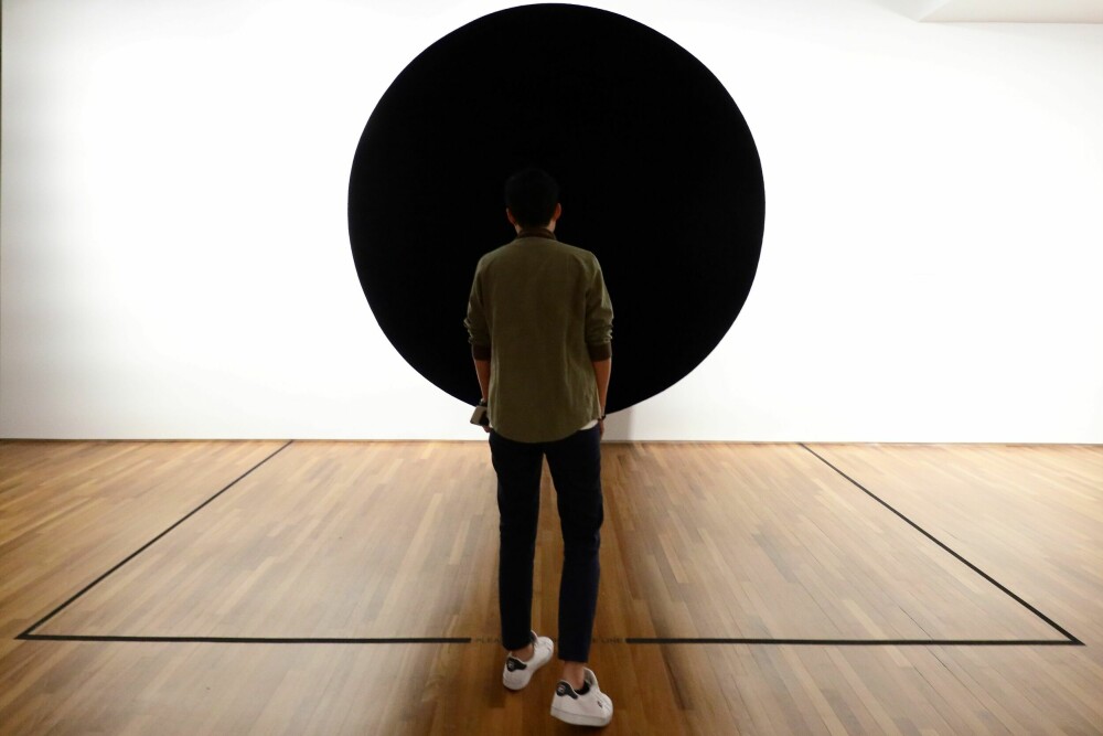 <b>SVART MINIMALISME:</b> En besøkende ser på et kunstverk av den britisk-indiske kunstneren Anish Kapoor som på engelsk har fått navnet «Void during Minimalism: Space. Light.» (Tomrom under minimalisme. Rom. Lys.). Dette bildet er tatt i 2018, da det var utstilt på National Gallery Singapore som ett av 150 kunstverk som alle omhandlet den minimalistiske kunstretningen.